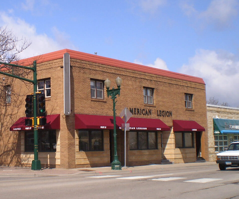 Photo of American Legion brick building with decorated burgundy awnings over windows and entrance